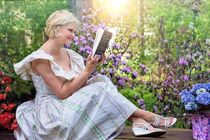 woman-sitting-while-reading-book-outdoors